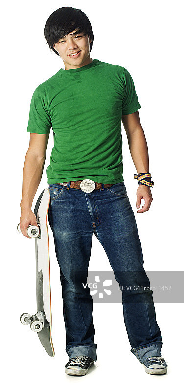 一个穿着牛仔裤和绿色衬衫的亚洲少年男子微笑着拿着他的滑板图片素材