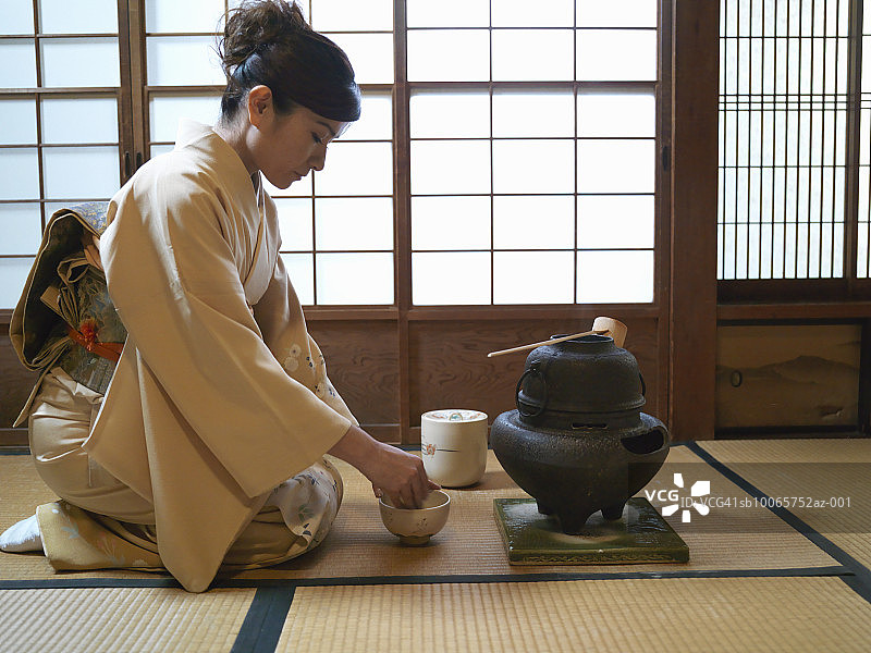 日本，东京，女人跪在地上，准备沏茶，侧视图片素材