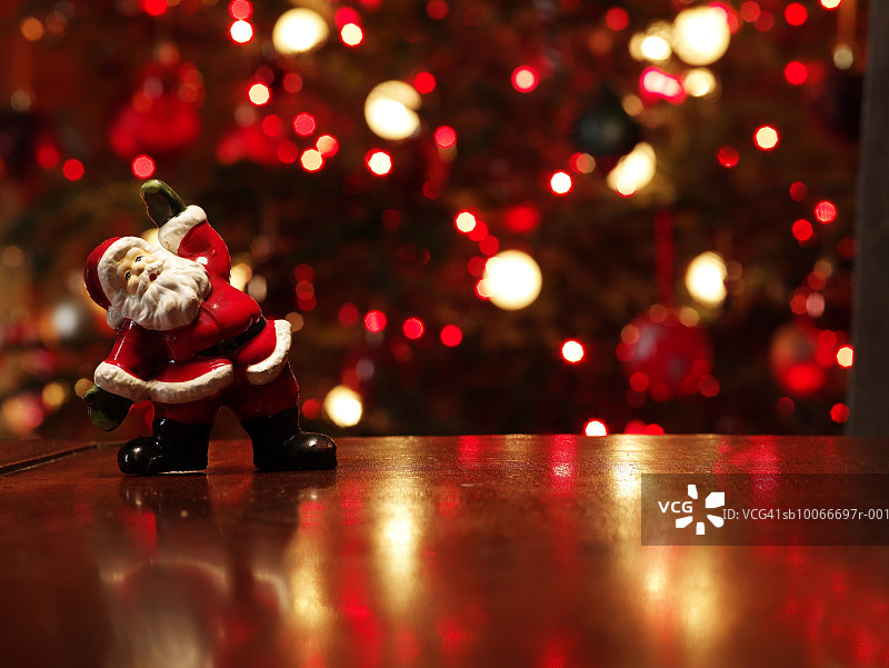 圣诞老人小雕像在圣诞树前的桌子上图片素材