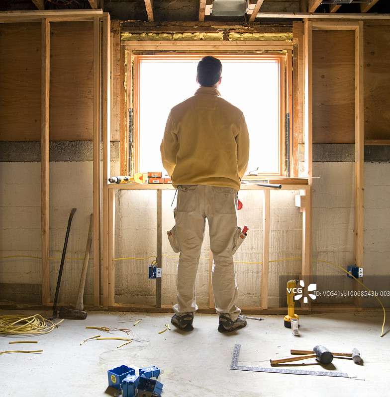 一名男子站在建筑工地，透过窗户望出去，后视镜图片素材