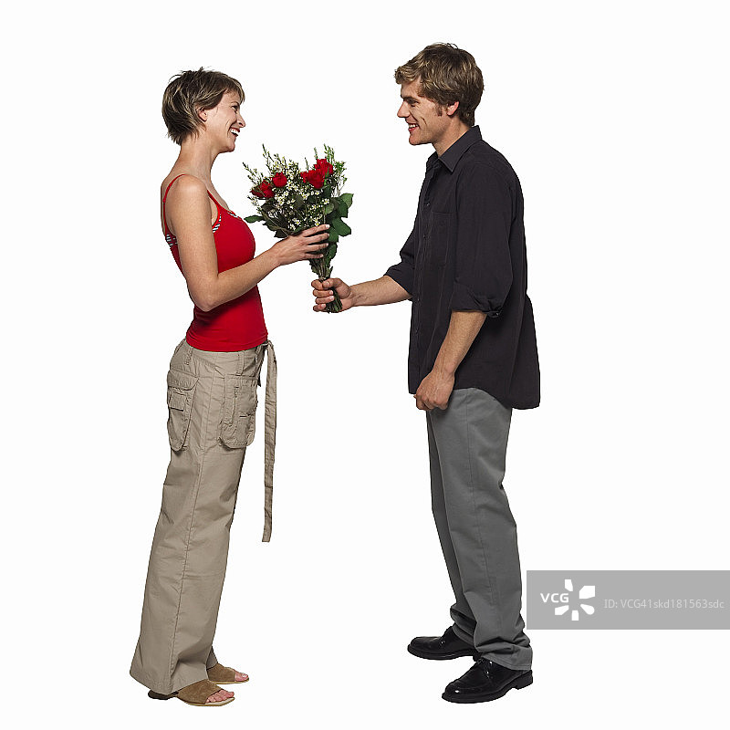 年轻男子给年轻女子一束玫瑰的侧视图图片素材