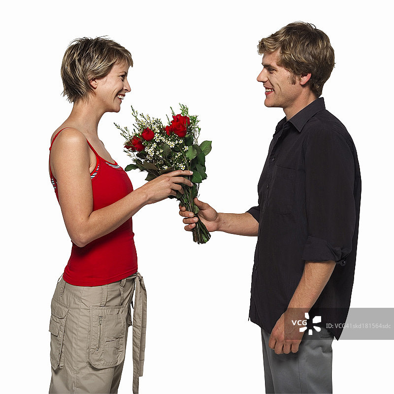 年轻男子给年轻女子一束玫瑰的侧视图图片素材