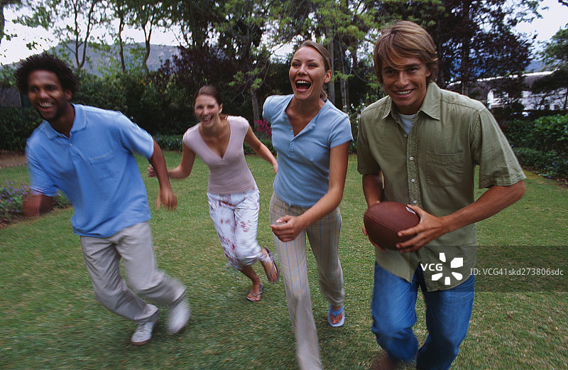 年轻男女在花园里踢足球图片素材