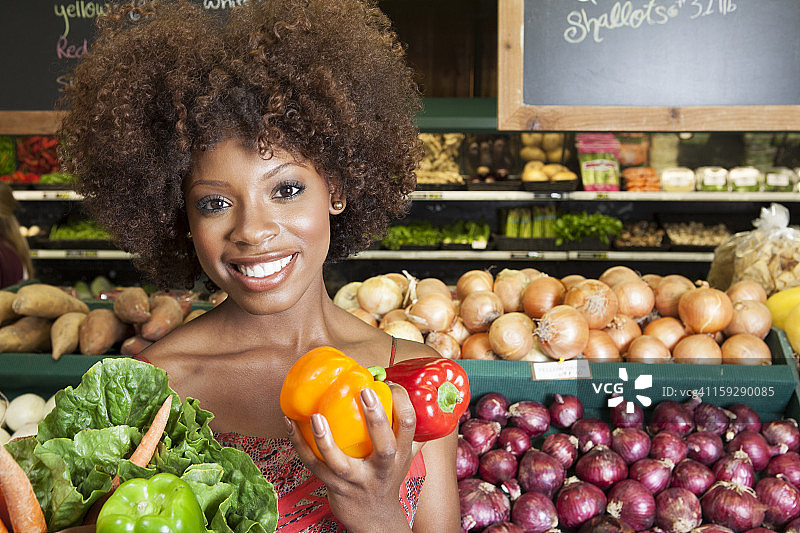 非裔美国妇女拿着青椒和蔬菜在超市图片素材