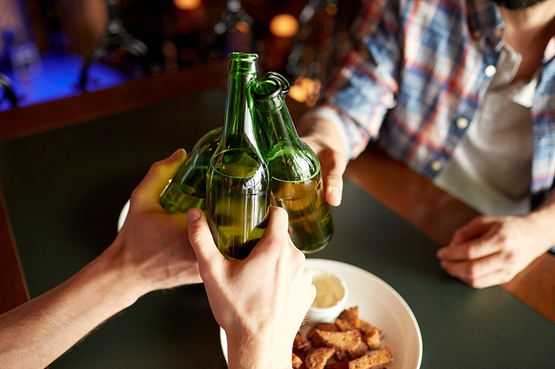 人们，男人，休闲，友谊和庆祝概念-近距离男性朋友喝啤酒和在酒吧或酒吧碰杯图片下载