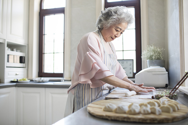 快乐的老年女子在厨房包饺子图片下载