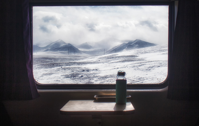 火车上窗外的雪山和桌子上的杯子图片下载