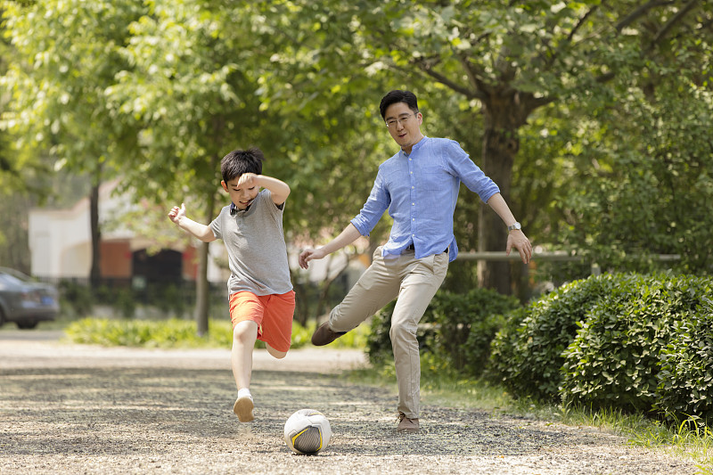 快乐的父子在草地踢足球图片素材