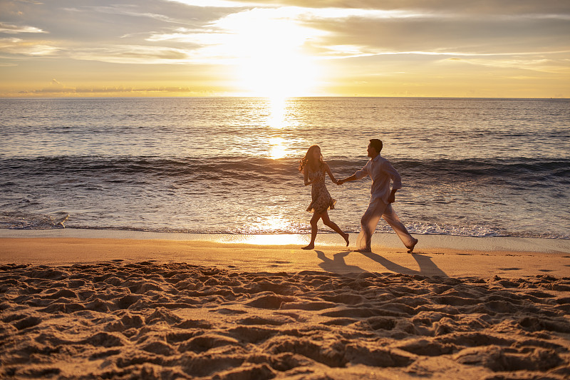 快乐的年轻夫妇在沙滩奔跑图片下载