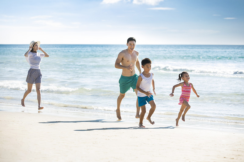 快乐的年轻家庭在沙滩奔跑图片素材