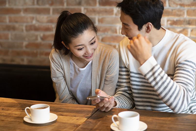 年轻情侣在咖啡店使用手机图片素材