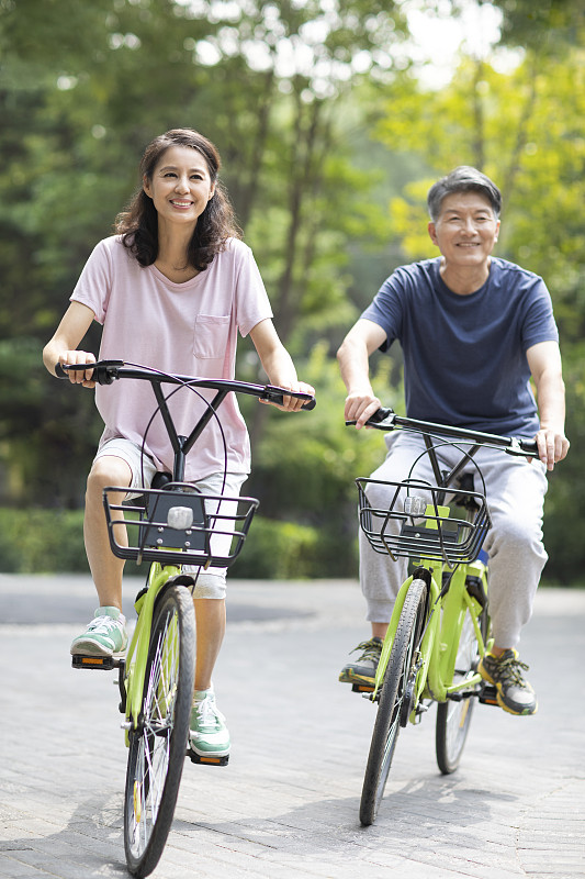 快乐的成熟夫妇在公园骑自行车图片下载