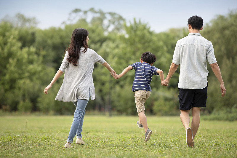 快乐年轻家庭在草地上散步图片下载