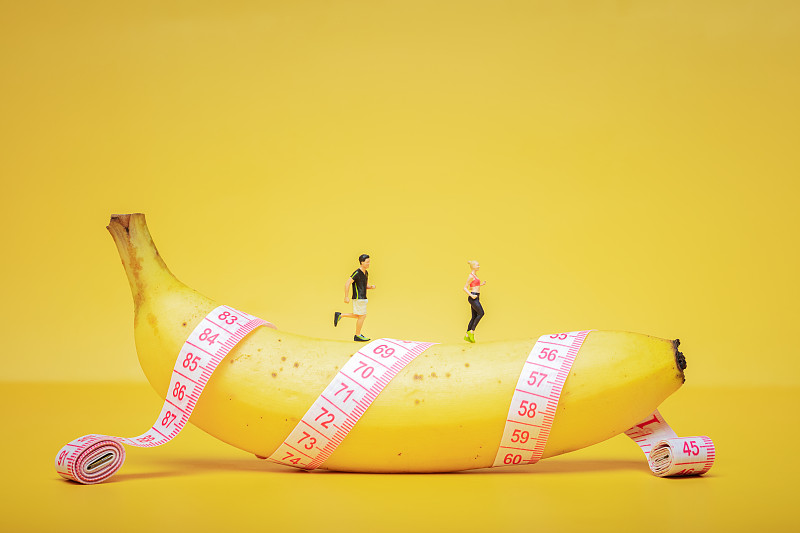 年轻人在皮尺卷着的香蕉上慢跑健身减肥瘦身健康生活图片下载
