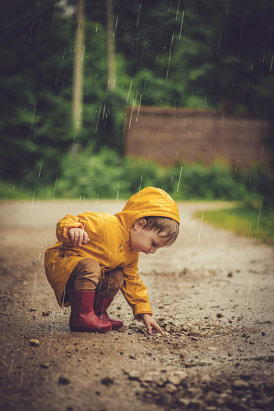小男孩在雨中在马路上玩耍图片下载