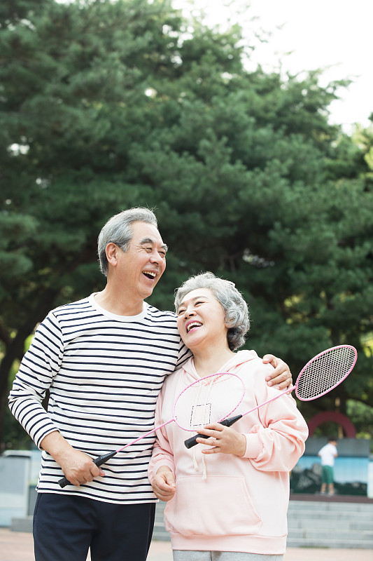 一对老夫妇在公园里笑着打羽毛球图片素材