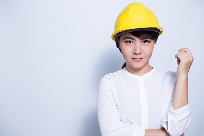 女工程师的肖像戴安全帽站在白色的背景图片下载