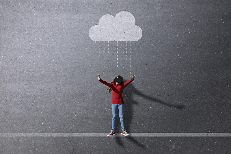 女孩戴着VR眼镜站在想象的彩绘雨云下图片素材