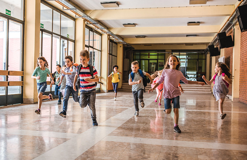 一大群小学生在学校走廊上奔跑。图片下载