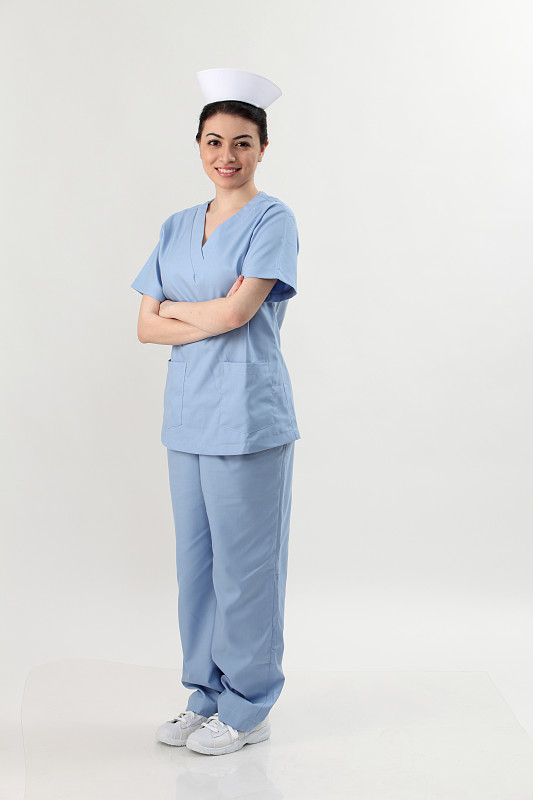 自信的年轻女护士站立双臂交叉的灰色背景的全长肖像图片素材