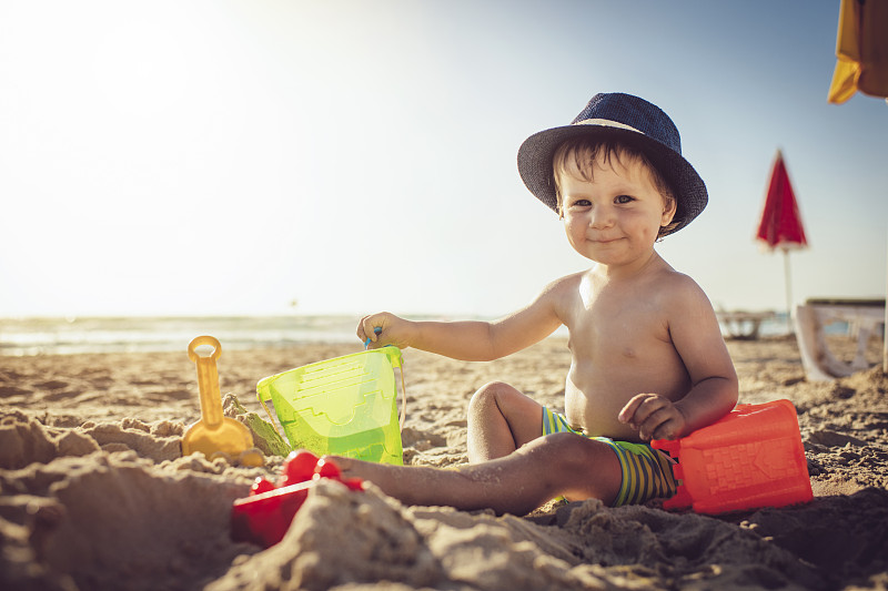 小男孩坐在沙滩上，在堆沙堡图片素材