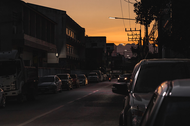 日落时分，街道上建筑物旁边的汽车图片素材