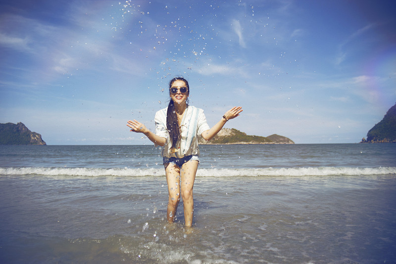 戴着太阳镜的女人在海中溅水的肖像图片下载