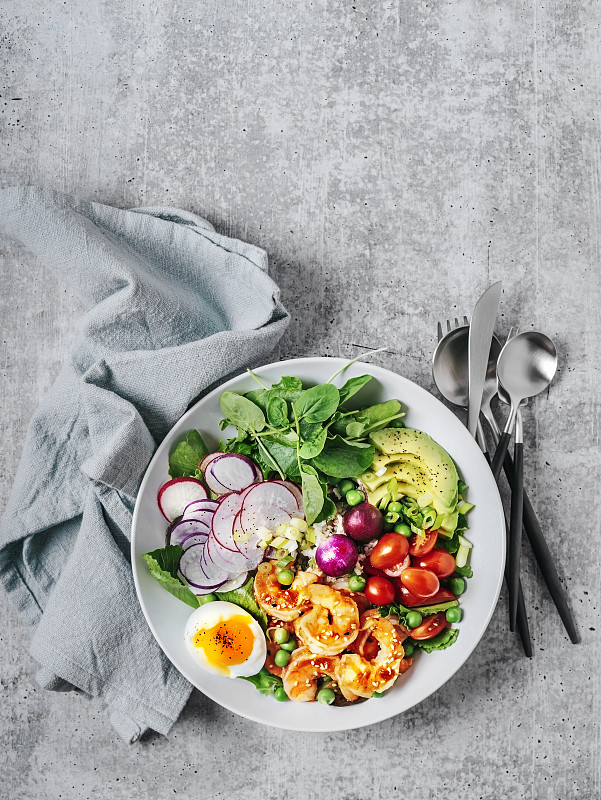 健康的午餐碗，有绿色蔬菜，鳄梨，樱桃番茄，萝卜，水煮鸡蛋和虾在灰色的背景图片下载