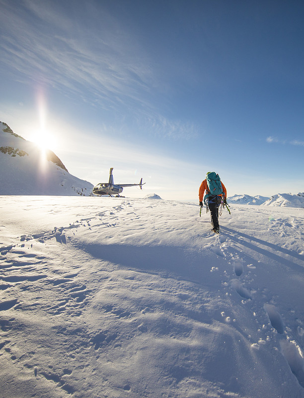 一个登山者接近他的直升机，等待冰川。图片素材