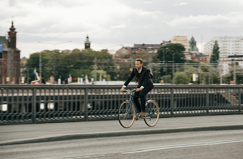 商人骑着自行车在城市街道上的天空图片下载