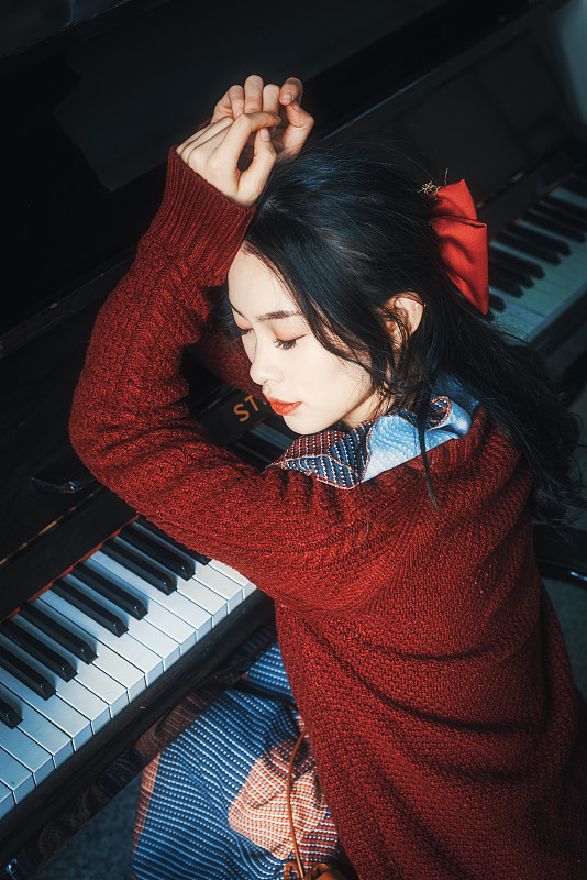 成都，一位年轻的中国女子坐在钢琴旁休息图片下载