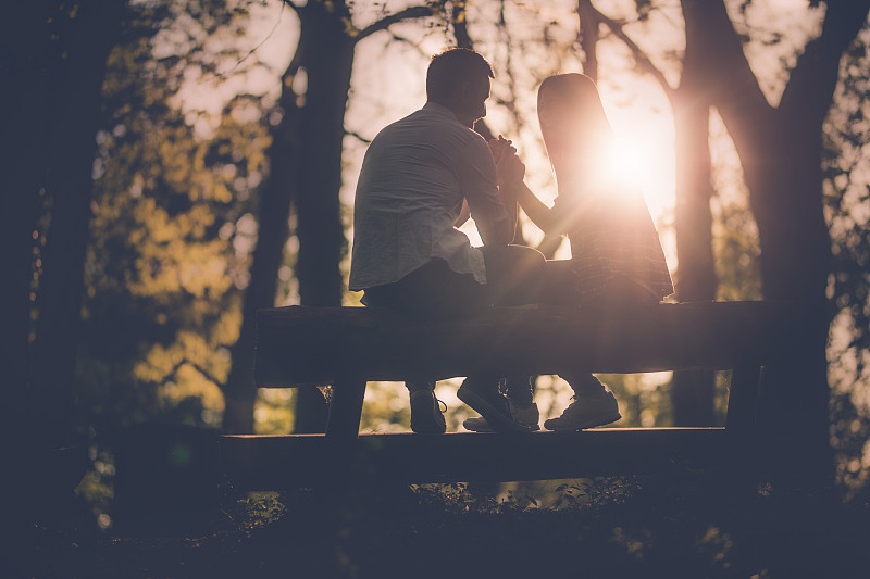 日落时分，一对年轻浪漫的情侣在长椅上聊天。图片下载