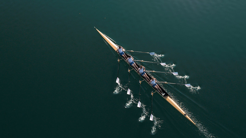 四个男运动员在阳光下在湖上划桨图片下载