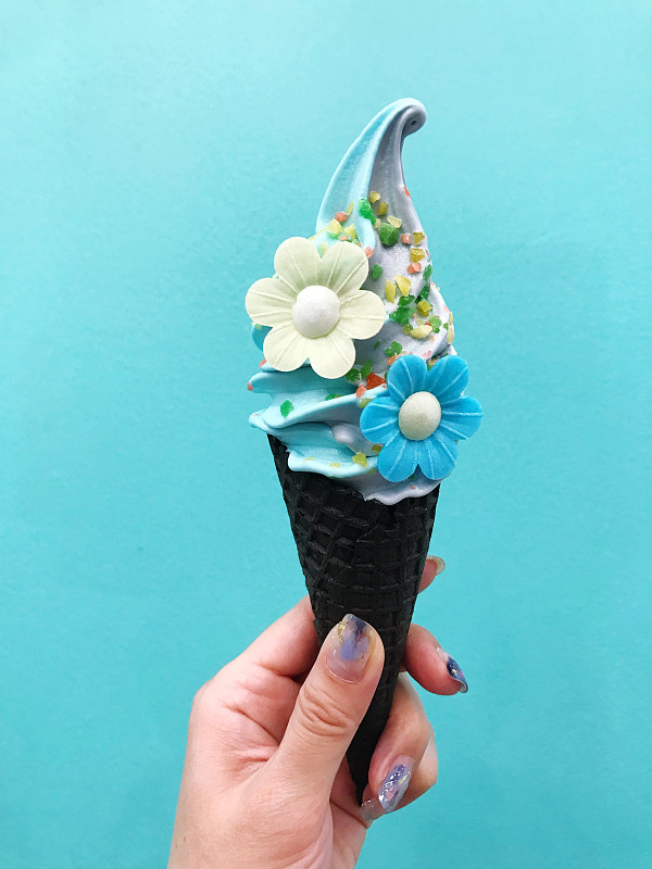 手握冰淇淋在蓝色背景的特写图片素材