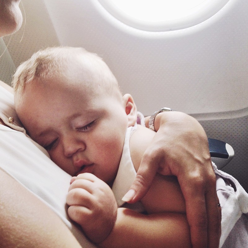 在飞机上，男婴睡在妈妈的腿上图片下载