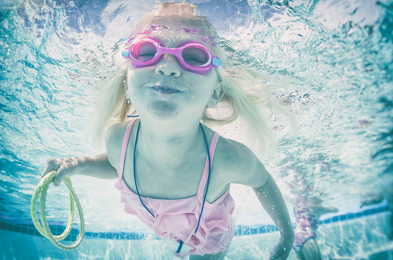 快乐的水下游泳小女孩戴着护目镜图片素材