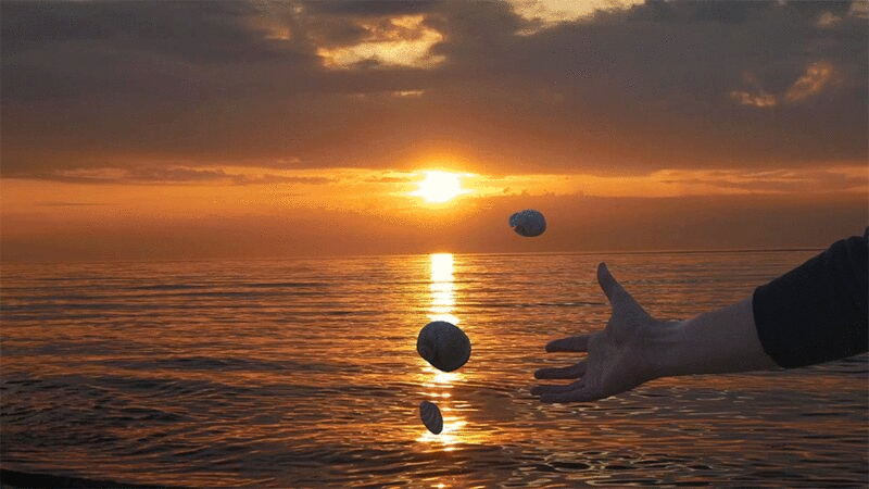 夕阳西下，人们往水里扔贝壳图片下载