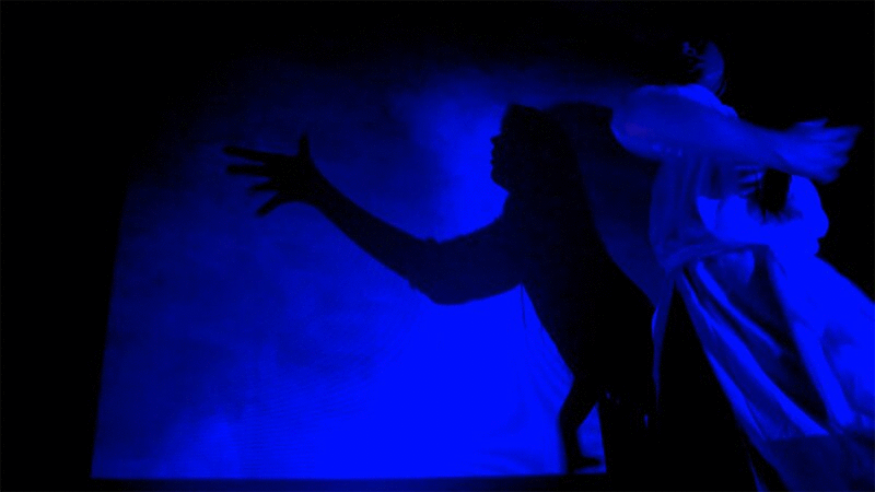 少女在蓝光中跳舞，影子在墙上移动图片下载