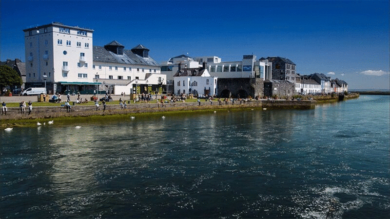 一群人沿着河岸放松，戈尔韦，爱尔兰图片下载