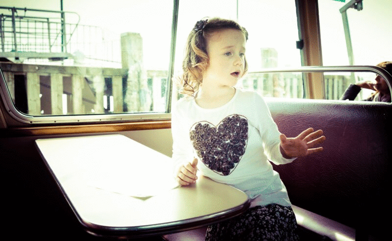衬衫上有心形图案的年轻女孩坐在摇摆渡船上图片下载