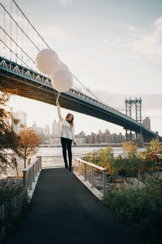 一个年轻的成年女子被桥附近的三个大气球举起来图片下载