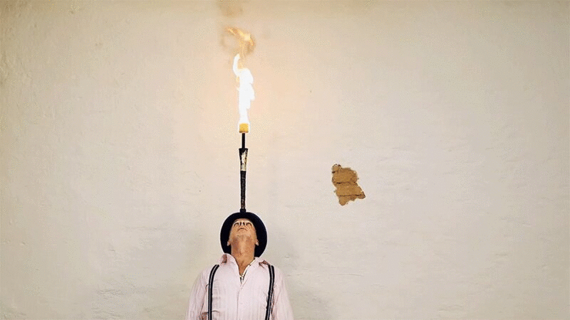 一名男子在头上平衡燃烧的木棍图片下载