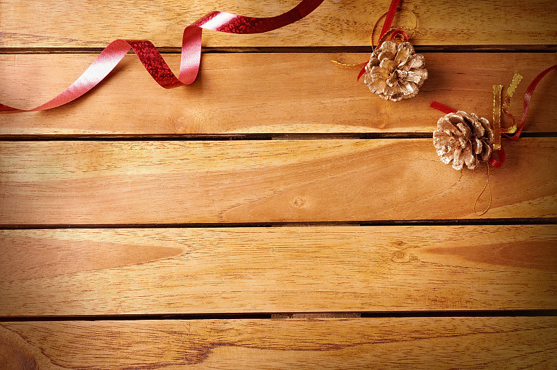 红色的丝带和松果圣诞装饰在木制的桌面上图片下载