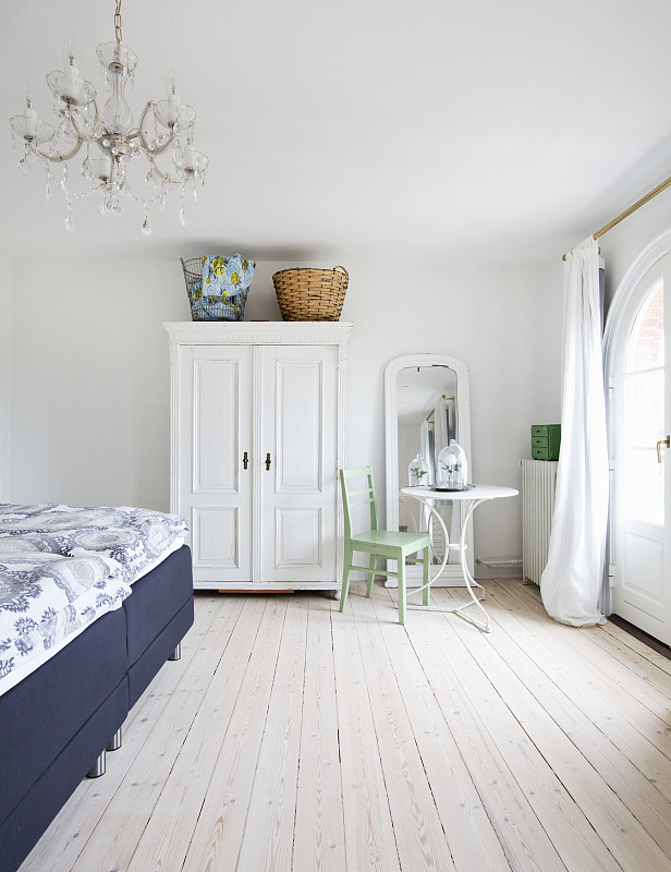 白色衣柜，圆桌和椅子，浅色木地板的卧室双人床图片素材