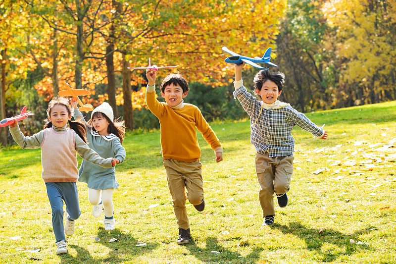 拿着玩具飞机在公园玩耍的快乐儿童图片下载