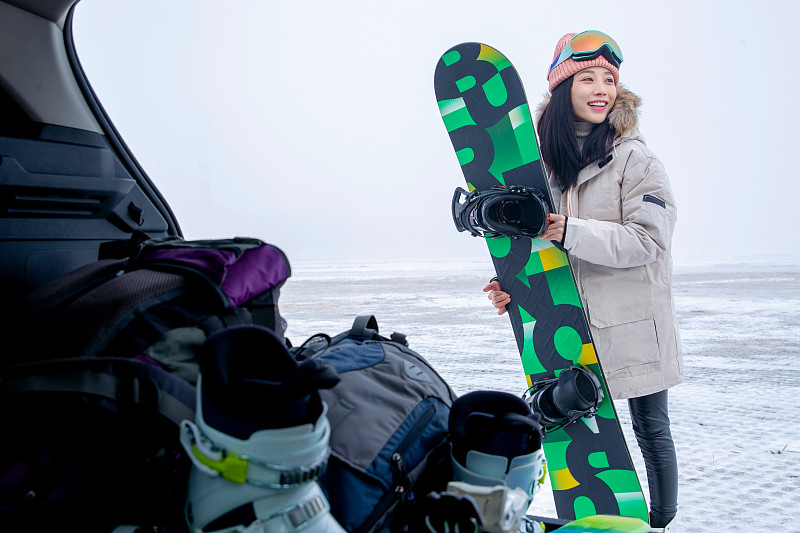 青年女人从后备箱拿单板滑雪板图片素材