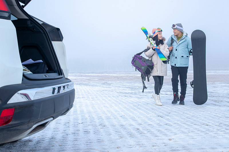 停车场上青年伴侣拿着滑雪板图片素材