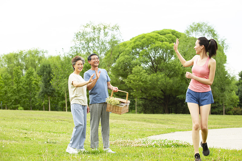 青年女子帮助老年夫妻拿野餐篮子后挥手告别在户外公园图片下载