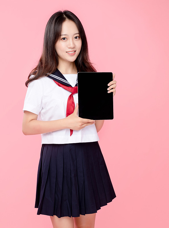 粉红色背景里，拿着平板电脑的可爱女学生图片素材