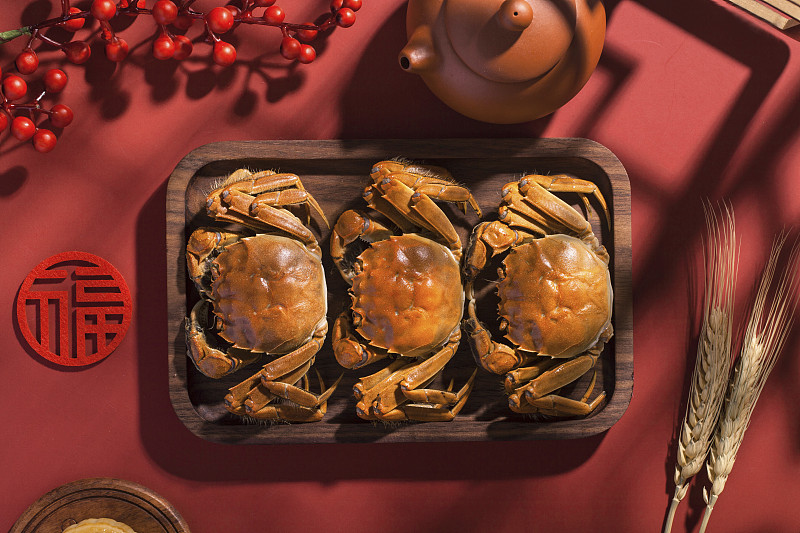 盛放在木盘里的三只美味的大闸蟹图片下载